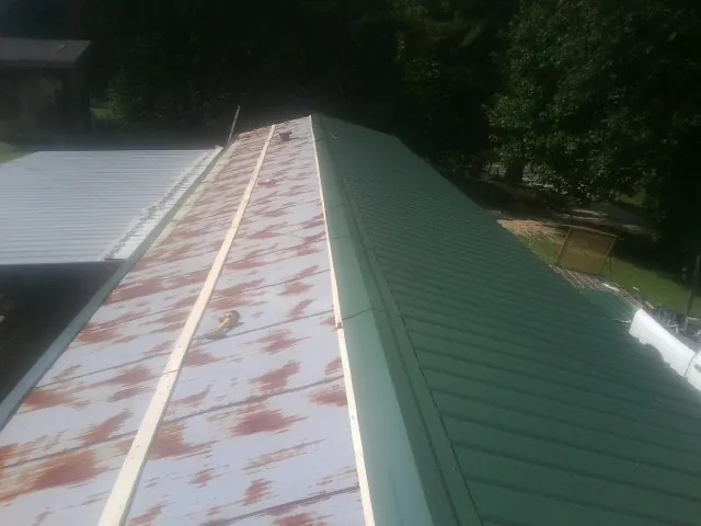 Old rusted panels beside newly installed green metal roofing — Wind Damage Roof Repair by Roofing Brothers in New Freeport