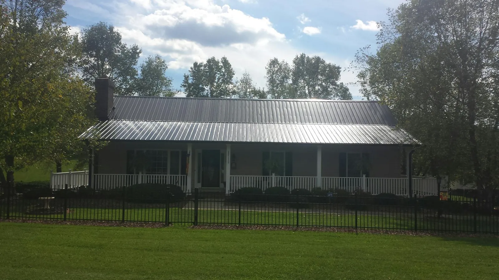Gray metal roof on a brick ranch with a full width front porch — Gutter Guard Installation work by our crew in New Freeport