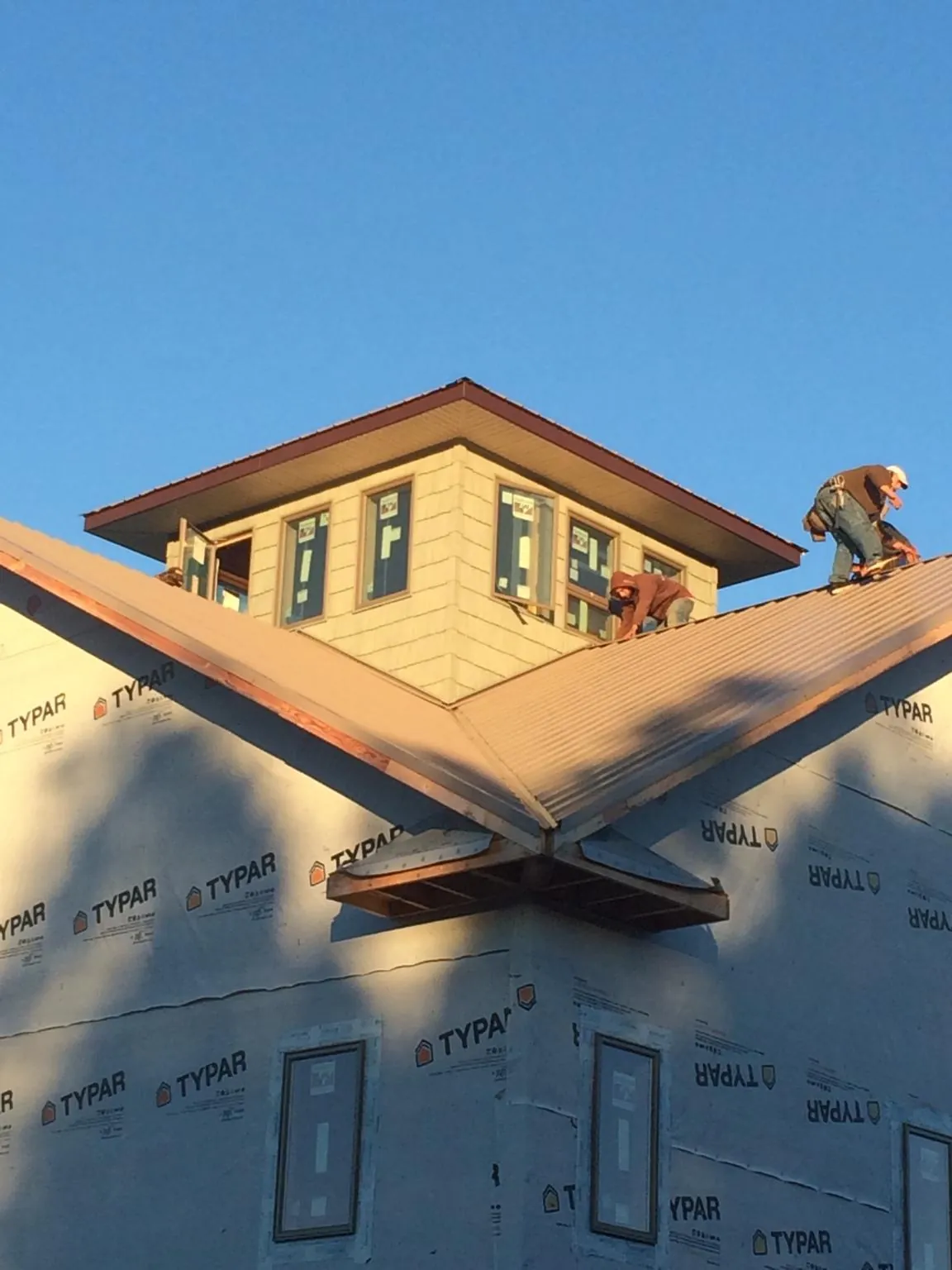Roofers working around a rooftop cupola on a new metal roof at sunset — Roof Waterproofing in New Freeport by Roofing Brothers